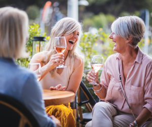 Two women smiling at each other holding glasses of wine